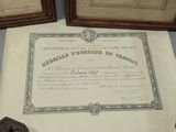 a certificate sitting on a table next to a pair of framed pictures