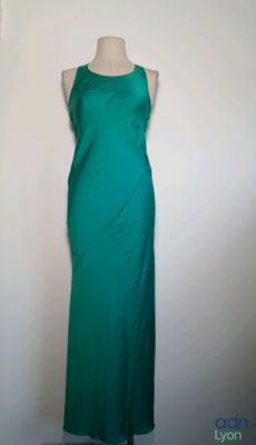 une robe verte posée sur un mannequin contre un mur blanc