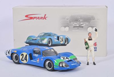 La boîte est ouverte et laisse apparaître une maquette de voiture de course bleue et un homme en costume blanc.