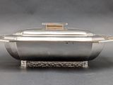 silver plated casserole with lid on stand on grey background