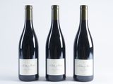 three bottles of wine are lined up on a white surface