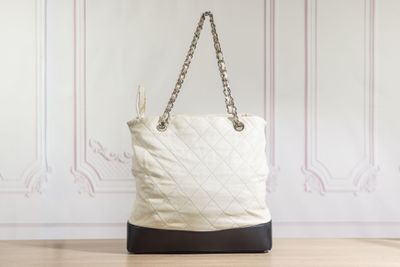 white quilted tote bag with chain handles on wooden floor