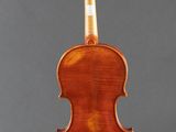 an antique violin on a stand with a gray background