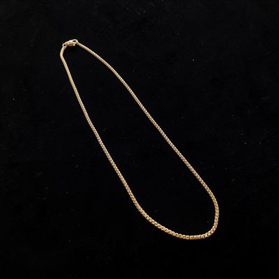 a gold necklace with a chain on a black background
