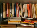 many books that are stacked on a shelf in the room