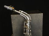 an old silver saxophone sitting on top of a box on a black background