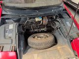a red car with its hood open and a tire in the trunk