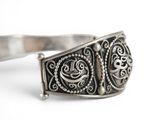 a close up of a silver bracelet with a flower design on it