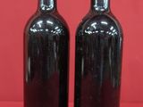 two bottles of wine sitting on top of a red surface