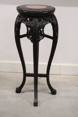une table noire avec un plateau en marbre posée sur un sol blanc