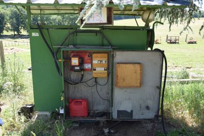 a small green building with a red canister on the side of it