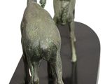 two statues of a goat and a goat on a black base