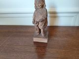 une petite statue représentant un enfant assis sur une table en bois