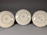 three white plates with gold rims on them sitting on a gray surface