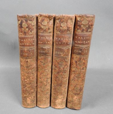four old books sitting on top of each other on a gray surface