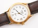 a gold wrist watch with a white dial on a brown leather strap