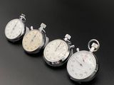 four stopwatchs are lined up on a black surface