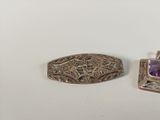 two pieces of silver and amethorate jewelry on a white surface