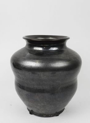 un vase noir posé sur une surface blanche