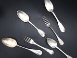 five silver spoons and two silver spoons on a black surface
