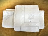 trois draps en lin blanc ornés de motifs brodés, posés sur une table