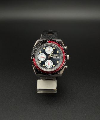 une image représentant une montre posée sur une surface noire, avec une lunette rouge