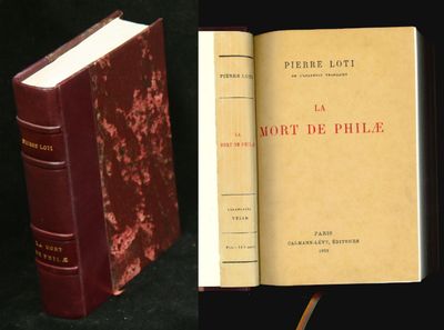 un vieux livre posé sur une table noire, à côté d'un livre rouge