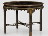 une table noire et dorée, dotée d'un plateau circulaire posé sur un socle blanc