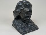 a close up of a statue of a man ' s head on a white surface
