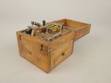 une vieille caisse en bois contenant des outils, posée sur une surface blanche