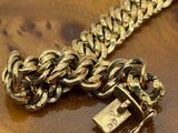 an image of a gold chain bracelet with a padlock on a wooden table