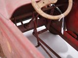 a red toy car with a steering wheel on a white surface