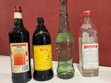 Plusieurs bouteilles d'alcool sont posées sur une table, avec un mur rouge en arrière-plan.
