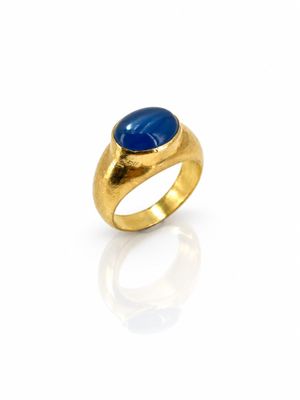 gros plan d'une bague en or avec une pierre bleue