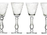 four wine glasses are lined up in a row on a white surface