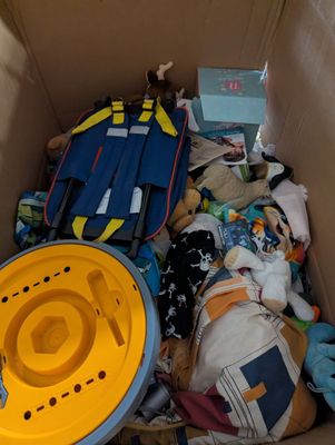 a cardboard box filled with clothes and a yellow hat