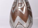 un vase brun et blanc posé sur une surface blanche