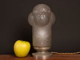 an apple sitting next to a glass lamp on a table
