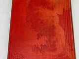 an old red book sitting on top of a white table