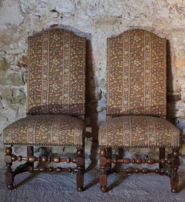 pair of antique upholstered chairs in front of a stone wall