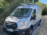 une camionnette argentée garée sur un chemin de terre, près des arbres