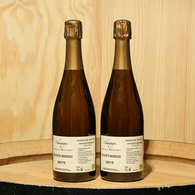 two bottles of wine sitting on top of a wooden barrel