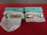 une paire d'ustensiles de service plaqués or, présentés dans leurs boîtes sur un fond rouge