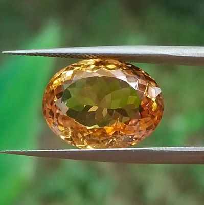 un gros plan d'un diamant jaune tenu par une paire de pinces