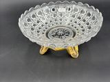 a clear glass bowl with gold legs on a black surface