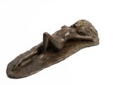 bronze sculpture of a woman laying on a leaf