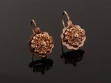 a pair of rose shaped earrings on a black surface