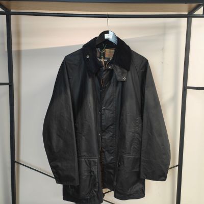 une veste en cuir noir accrochée à un portant devant un mur blanc