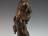 statue of a woman holding a basket of flowers on a white surface