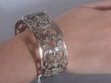 Quelqu'un porte un bracelet en argent orné d'un motif floral.
